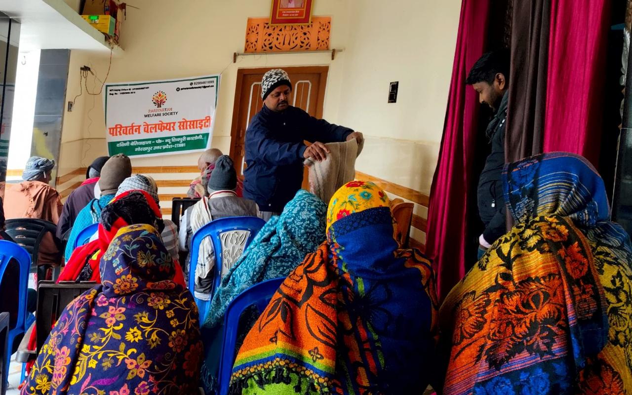 Volunteers distributing thick blankets to people outdoors